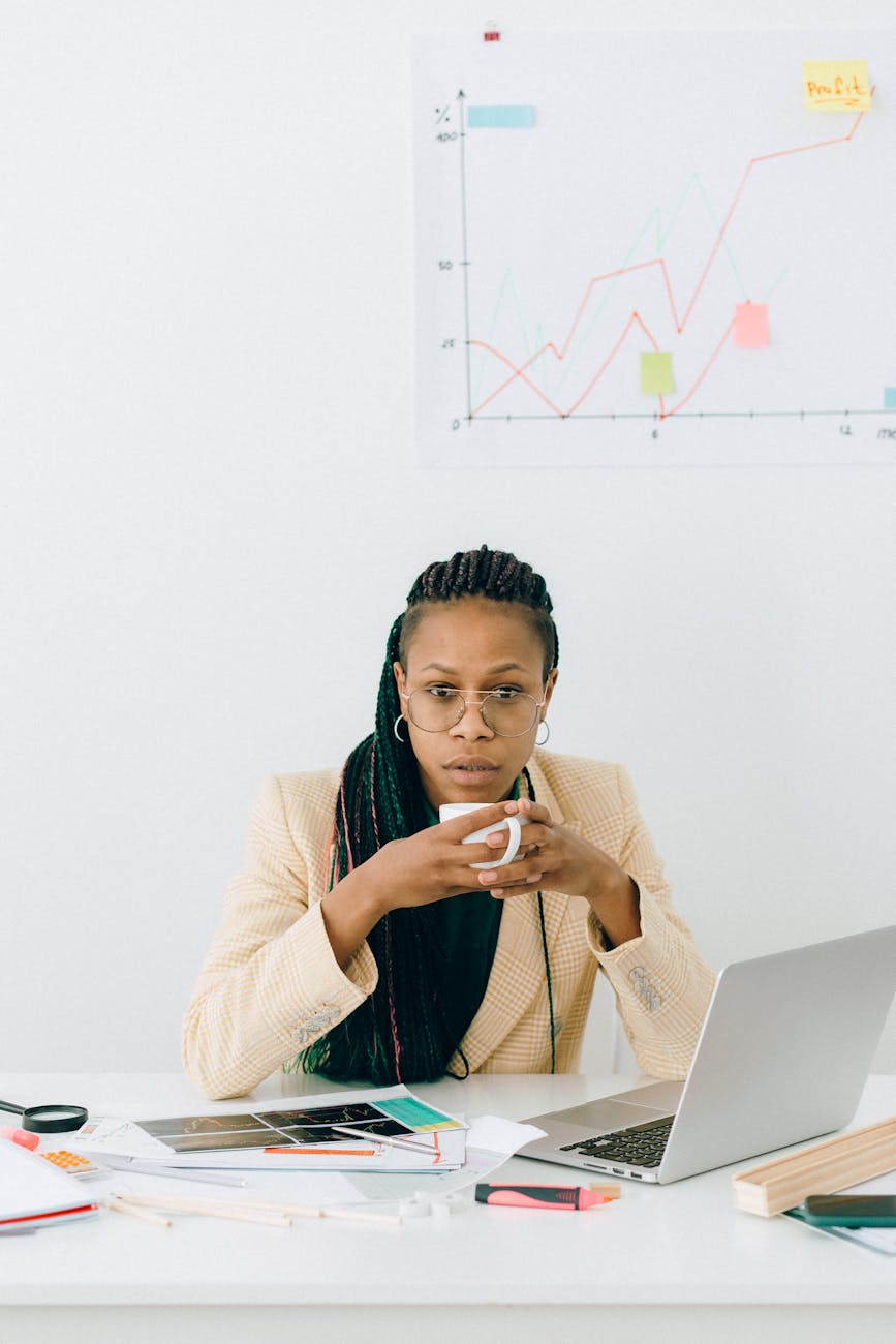 a woman drinking a cup of coffee while working